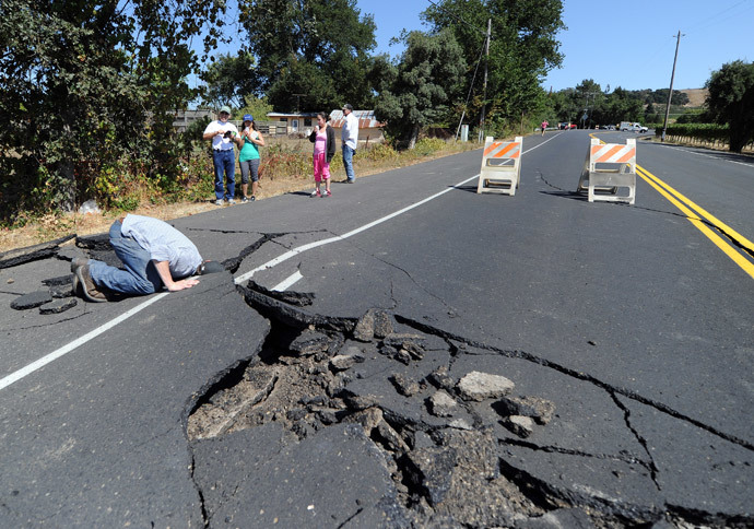 Nicholas George looks under a buckled highway just outside of Napa, California after earthquake struck the area in the early hours of August 24, 2014.(AFP Photo / Josh Edelson )