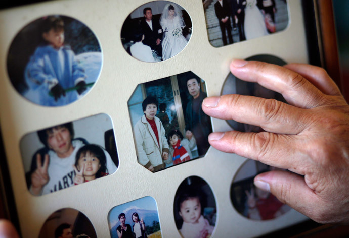 Mikio Watanabe touches a photograph of his late wife Hamako (L), himself (R) and their grandchild at his home at Yamakiya district in Kawamata town, Fukushima prefecture June 23, 2014.(Reuters / Issei Kato)