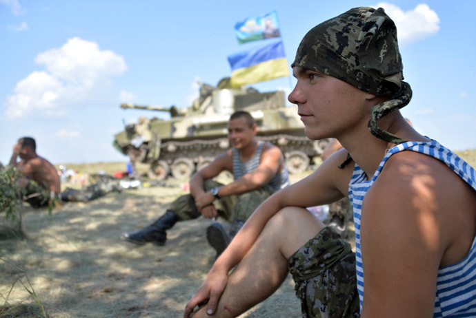 Ukrainian servicemen rest in the shade next to an armoured vehicle topped with a Ukrainian flag as they take up a position near the eastern city of Debaltceve, in the region of Donetsk, on July 30, 2014. (AFP Photo/Genya Savilov)