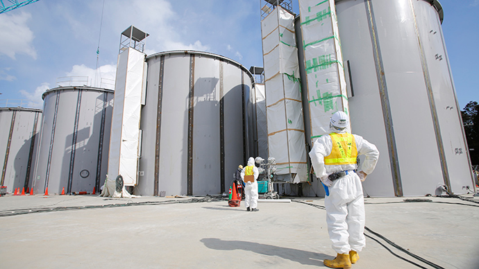 A worker wearing a protective suit and a mask looks up welding storage tanks for radioactive water, under construction in the J1 area at the Tokyo Electric Power Co's (TEPCO) tsunami-crippled Fukushima Daiichi nuclear power plant in Okuma in Fukushima prefecture (AFP Photo / Toru Hanai)