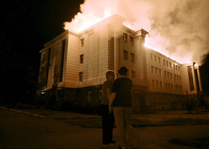 Bystanders watch a fire consuming a school in downtown Donetsk on August 27, 2014, after being hit by a shelling. (AFP Photo / Francisco Leong)