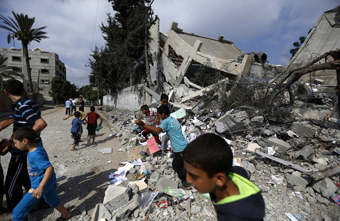 Palestinian children run near what remains of Ali ibn Abi Taleb government school after it was targeted overnight by Israeli airstrikes on August 26, 2014 in Gaza City. (AFP Photo / Mohammed Abed)