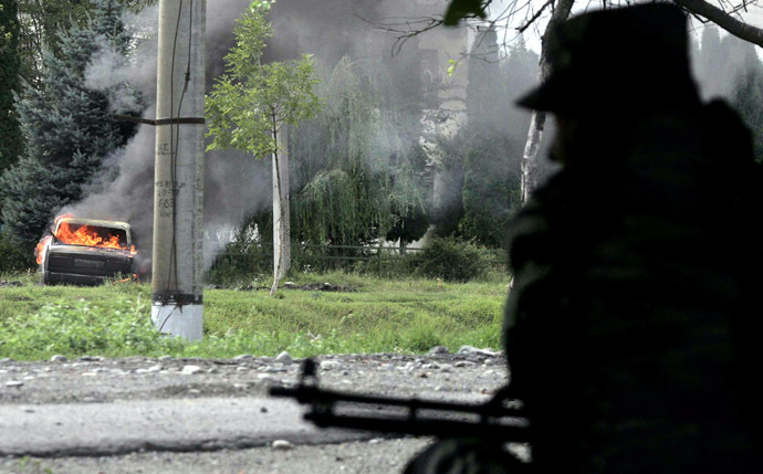 A Russian soldier waits on his position as a car burns outside the school where a group of gunmen, wearing belts laden with explosives, are holding civilian hostages in a school in the northern Ossetian town of Beslan, some 30 kms outside Vladikavkaz, 02 September 2004. (AFP Photo/Maxim Marmur)