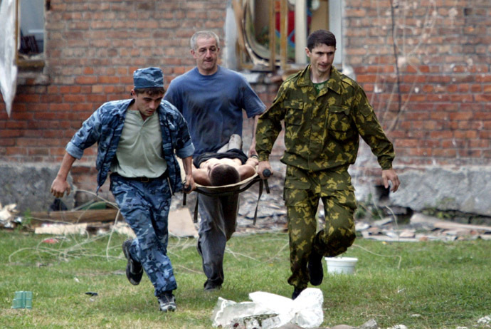 Volunteers carry an injured civilian to safety after soldiers stormed a school seized by heavily armed masked men and women in the town of Beslan in the province of North Ossetia near Chechnya , September 3, 2004. (Reuters)