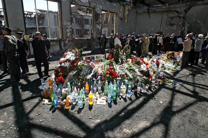 Ossetians mourn around flowers and bottles of water at the gymnasium of the destroyed school in Beslan, North Ossetia, 08 September 2004. (AFP Photo/Victor Drachev)