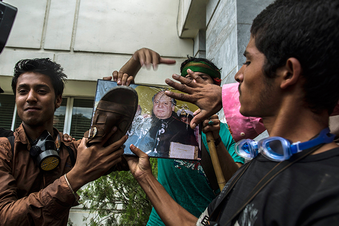 Supporters of Tahir ul-Qadri, a Sufi cleric and leader of Pakistan Awami Tehreek (PAT) party, use a sandal to hit a portrait of Prime Minister Nawaz Sharif, as a sign of disrespect, after storming the building of the state television channel PTV, during the Revolution March in Islamabad September 1, 2014 (Reuters / Zohra Bensemra)
