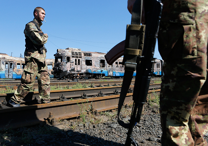 Anti-goverment fighters stand in front of destroyed trains at a railway station in the eastern Ukrainian town of Ilovaysk August 31, 2014 (Reuters / Maxim Shemetov)
