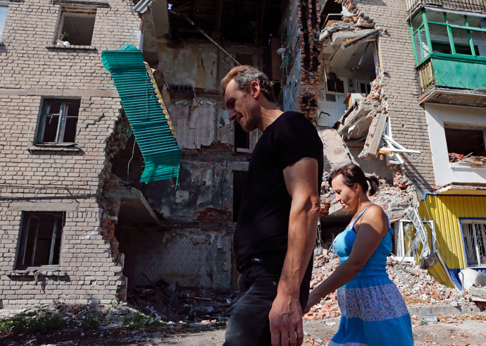 People walk past a building damaged by shelling in Snizhne (Snezhnoye), Donetsk region, August 29, 2014.(Reuters / Maxim Shemetov)