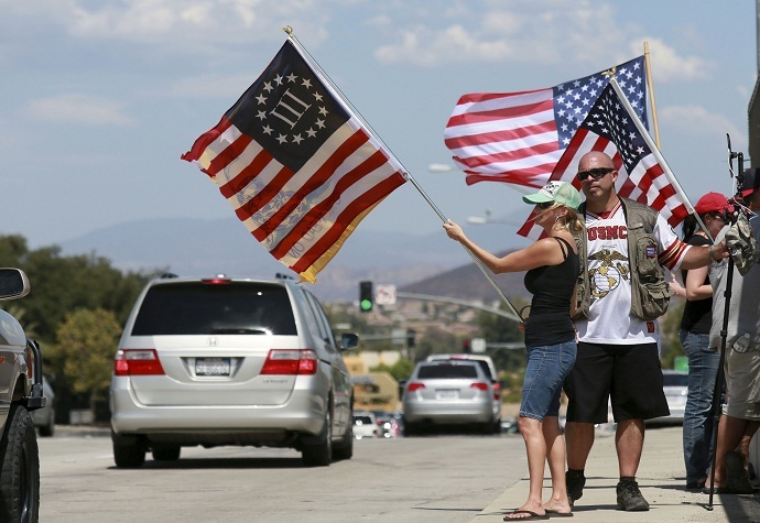 Anti-immigration protesters wave flags at motorists in Murrieta, California on July 19, 2014 (Reuters/Sandy Huffaker)