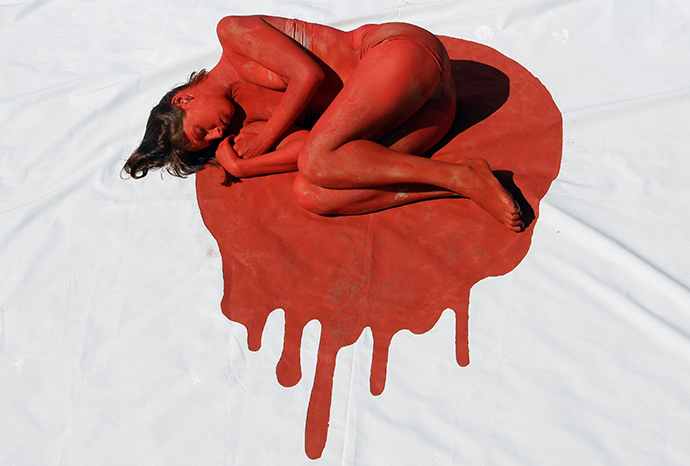 An animal rights activist covered in red paint lies on a white sheet made to look like a Japanese flag during a protest against dolphin and small whale slaughter, Madrid, September 3, 2008. (Reuters / Susana Vera)