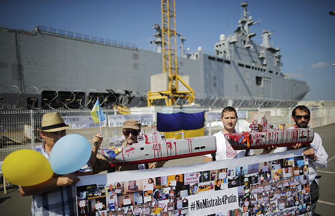 People hold up models of the Mistral-class helicopter carrier warship during a demonstration against a contract to deliver the warship to Russia, at the STX Les Chantiers de l'Atlantique shipyard site in Saint-Nazaire, September 7, 2014. (Reuters / Stephane Mahe)