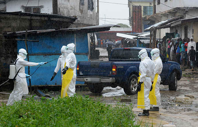 Health workers wearing protective clothing disinfect themselves after an abandoned dead body presenting with Ebola symptoms was found at Duwala market in Monrovia (Reuters / 2Tango)
