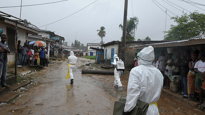 Health workers wearing protective clothing prepare to carry an abandoned dead body presenting with Ebola symptoms at Duwala market in Monrovia (Reuters / 2Tango)