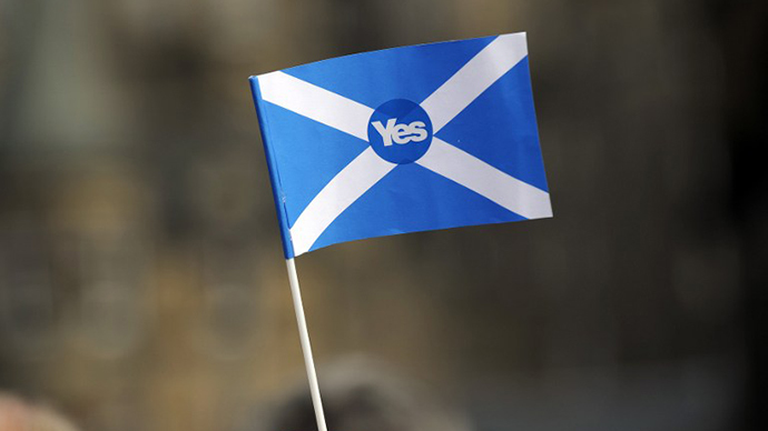 A pro-independence supporter holds a "Yes" flag as Scottish MP Jim Murphy addresses pro-union "Better Together" campaign supporters in Edinburgh on September 8, 2014. (AFP Photo / Andy Buchanan)
