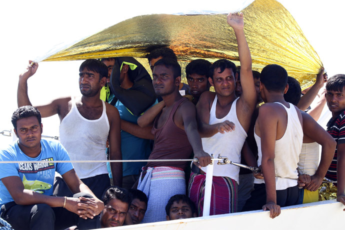 Migrants take shelter from the sun before disembarking a coast guard ship at the Sicilian harbour of Augusta, August 26, 2014. (Reuters/Antonio Parrinello)