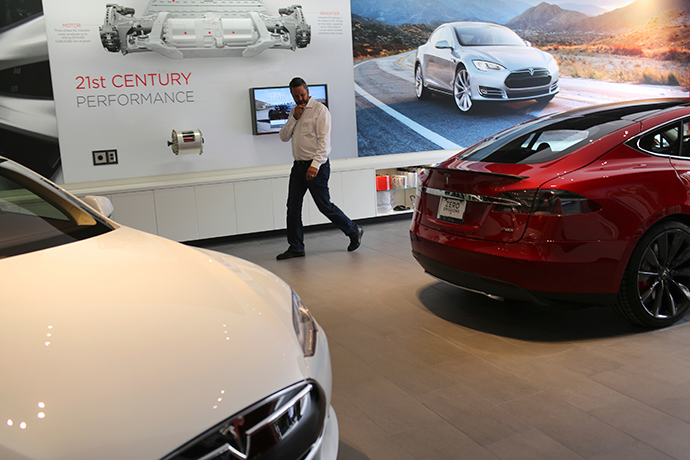 A man looks over a pair of Tesla Model S electric automobiles at a Tesla Motors showroom (Reuters / Robert Galbraith)