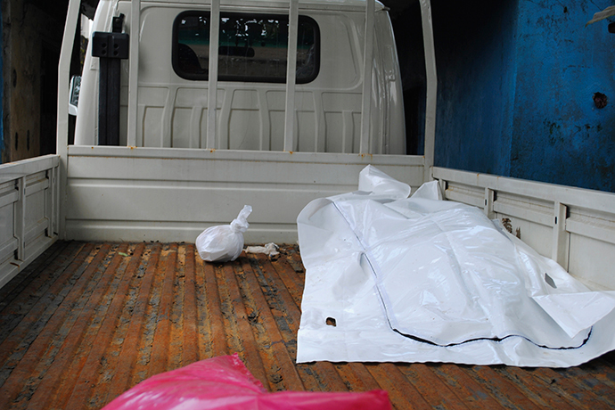 The body of a victim of Ebola virus is seen covered with a sheet at the back of a truck after health workers collected it in Monrovia, September 13, 2014. (Reuters / James Giahyue)