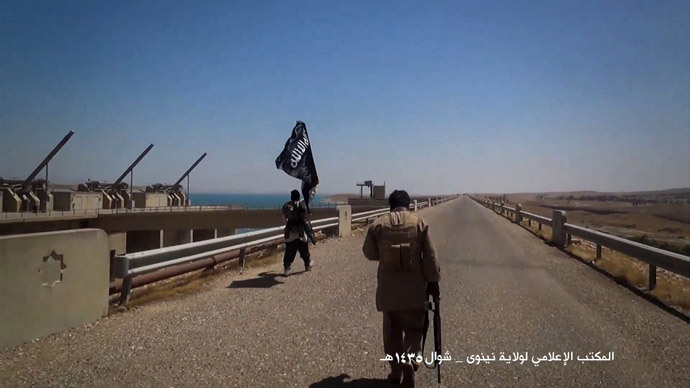 Islamic State (IS) militants waving the trademark Jihadits flag as they inspect the grounds of the Mosul dam on the Tigris river, on the southern shores of Mosul (AFP Photo / HO / Welayat Nineveh Media Office)