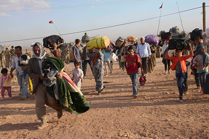 Syrian Kurds walk with their belongings after crossing into Turkey at the Turkish-Syrian border, near the southeastern town of Suruc in Sanliurfa province, September 20, 2014 (Reuters / Stringer)