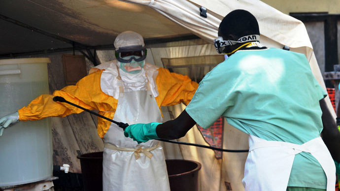 A Guinea health worker wearing a protective suit is sprayed down as he joins members of the Medecins sans frontieres Ebola treatement centre near the main Donka hospital in Conakry on September 25, 2014.(AFP Photo / Cellou Binani)