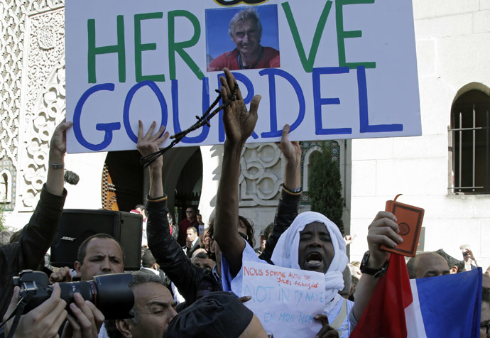 A man holds a placard which reads "Homage to Herve Gourdel", a French mountain guide who was beheaded by an Algerian Islamist group, during a gathering of Muslims in front of the Paris Mosque after Friday prayers September 26, 2014. (Reuters/Jacky Naegelen)
