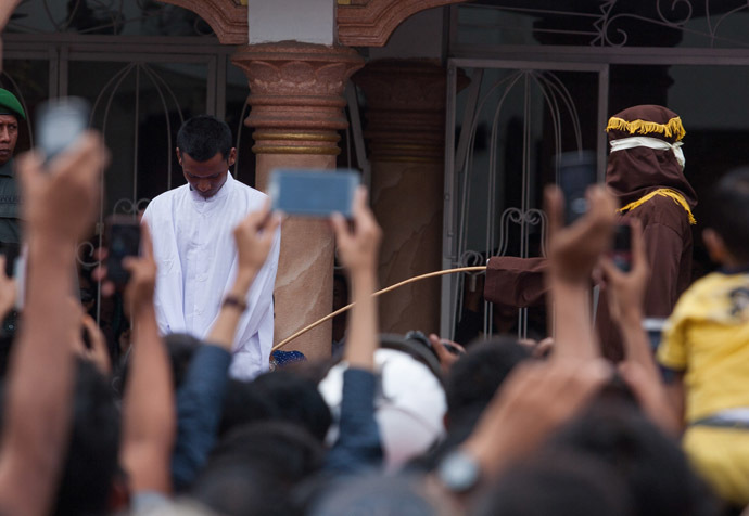 This picture taken in Banda Aceh on September 19, 2014 shows a hooded official (R, brown) caning an Aceh man for gambling in Aceh. Lawmakers in Indonesia's Aceh will vote on September 26 on whether to make gay sex punishable by 100 lashes of the cane, the latest proposed Islamic regulation in the conservative province that has outraged rights activists. (AFP Photo/Chaideer Mahyuddin)