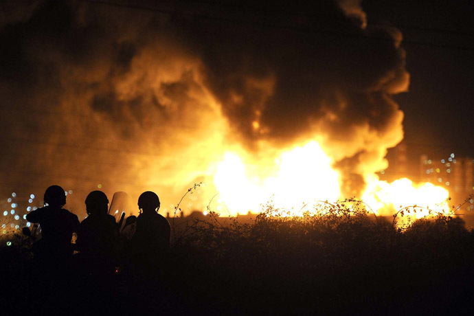 Men stand as flames arise after a fire broke out at the Mediterranean Refinery of Milazzo, one of most important in southern Italy, in Milazzo, near Messina on Sicily Island on September 27, 2014. (AFP Photo/Giovanni Isolino)