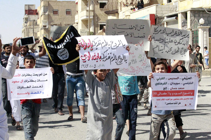 RYouths carry banners during a protest against the U.S. airstrikes on the Islamic State (IS) in Raqqa September 26, 2014. The banners in Arabic read, "By the soul, by the blood, we sacrifice ourselves oh state. by the soul, by the blood, we sacrifice ourselves oh Baghdadi" (C),"Who did not die by Assad's planes, died by Saudi family planes, The planes became many, but the strikes are one" (L). (Reuters)