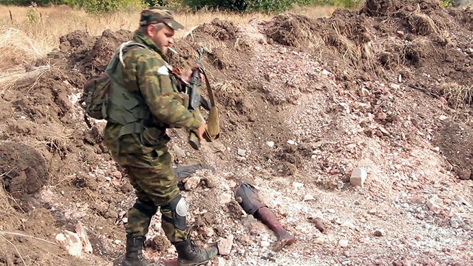 A Donetsk People's Republic militiaman is at the site of the graves of peaceful residents discovered near Mine 22 "Kommunar" outside Donetsk (stills from video courtesy of the Ruptly international news agency / RIA Novosti)