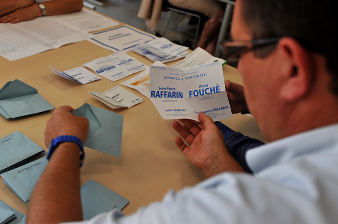 A man holds a vote for the former Prime Minister and opposition UMP party senator Jean-Pierre Raffarin during the senatorial election's vote counting, on September 28, 2014 in Poitiers. (AFP Photo / Guillaume Souvant)