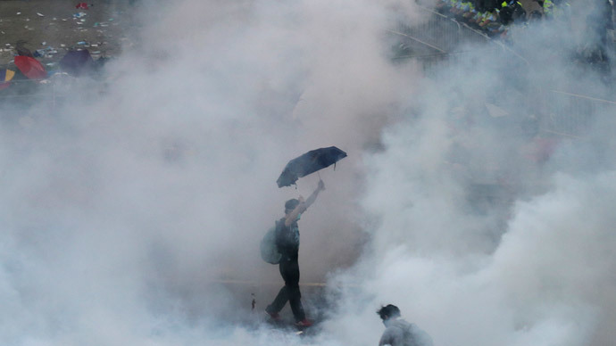A protester walks in tear gas fired by riot policemen after thousands of protesters blocking the main street to the financial Central district outside the government headquarters in Hong Kong September 28, 2014.(Reuters / Stringer )