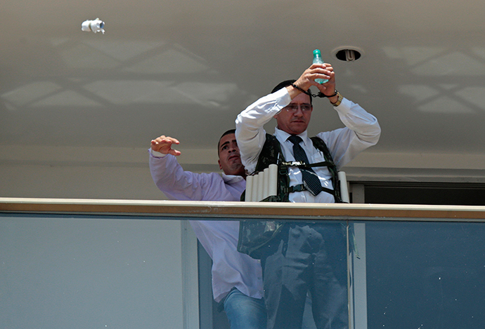 An unidentified man (L) throws an object from the balcony where he is holding an employee of the Saint Peter Hotel as a hostage, after forcing the employee to put on what he claims is a vest loaded with explosives, in Brasilia, September 29, 2014. (Reuters / Ueslei Marcelino) 