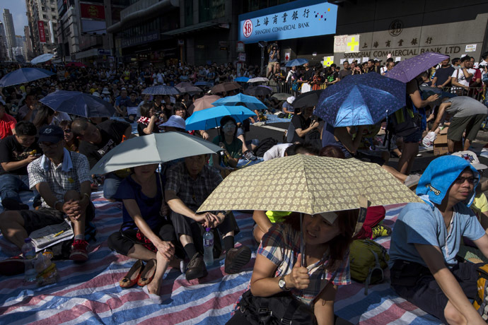 Protesters sit under umbrellas at a main street at Mongkok shopping district after thousand of protesters blocked the road in Hong Kong October 1, 2014. (Reuters/Tyrone Siu)