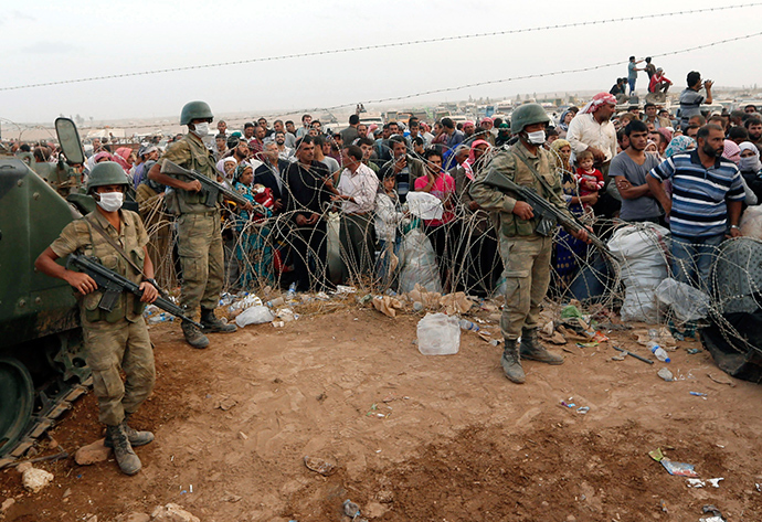Turkish soldiers stand guard as Syrian Kurdish refugees wait behind the border fences to cross into Turkey near the southeastern town of Suruc in Sanliurfa province September 27, 2014 (Reuters / Murad Sezer)