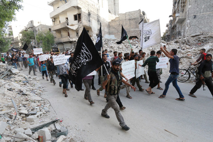 Supporters of Al-Qaeda's Syria affiliate Al-Nusra Front hold placards calling Syrian President Bashar al-Assad a "terrorist" and denouncing Arab states that have joined anti-Islamic State group campaign, as they demonstrate in the northern city of Alepppo on September 24, 2014. (AFP Photo / Zein Al Rifai)