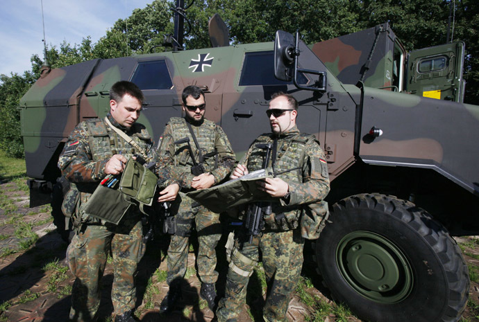 Three Bundeswehr army soldiers stand in front of a 'Dingo`, a German armored vehicle made by Krauss-Maffei Wegmann (KMW), at the Joint Support Service base in Grafschaft near the western German city of Bonn July 12, 2011. (Reuters/Wolfgang Rattay)