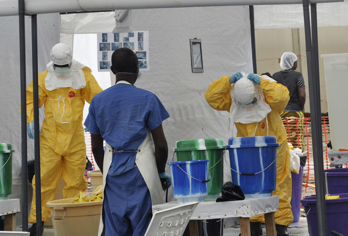 A Doctors Without Borders health worker takes off his protective gear under the surveillance of a colleague at a treatment facility for Ebola victims in Monrovia September 29, 2014. (Reuters/James Giahyue)