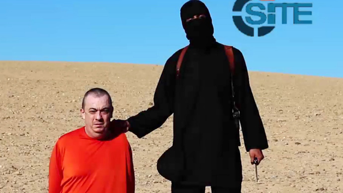 Masked militant (R) threatening to execute British hostage Alan Henning dressed in orange and on his knees in a desert landscape (AFP Photo / Site Intelligence Group / HO) 