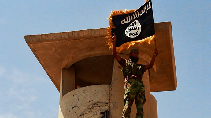 A militant of the Islamic State of Iraq and the Levant (ISIL) posing with the trademark Islamists flag after they allegedly seized an Iraqi army checkpoint in the northern Iraqi province of Salahuddin (AFP Photo / HO)