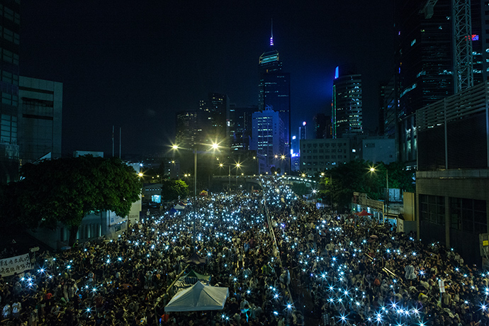 Pro-democracy protestors hold up their mobile phones after heavy rain in Hong Kong on September 30, 2014 (AFP Photo / Anthony Wallace)
