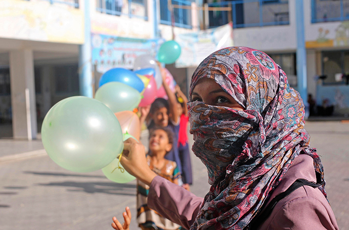 Palestinians, whose houses were destroyed during a seven-week Israeli offensive, hold balloons to decorate a United Nations-run school where they take refuge ahead of Eid al-Adha in Khan Younis, in the southern Gaza Strip October 3, 2014 (Reuters / Ibraheem Abu Mustafa)