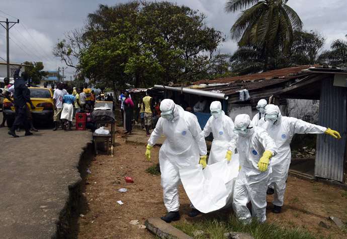 Red Cross workers carry away the body of a person suspected of dying from the Ebola virus, in the Liberian capital Monrovia, on October 4, 2014. (AFP Photo / Pascal Guyot)