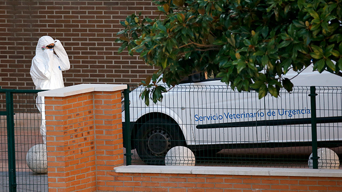 A worker adjusts protective clothing next to an emergency veterinary services vehicle parked outside the entrance of the apartment building of the nurse who contracted Ebola, in Alcorcon, outside Madrid, October 8, 2014 (Reuters / Susana Vera)