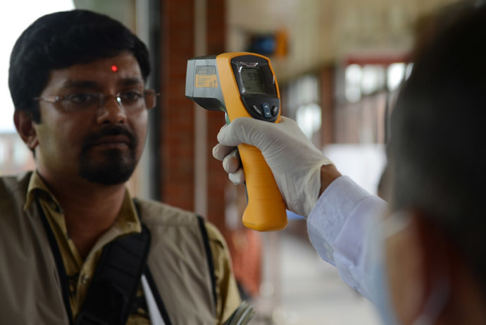 A Nepalese health worker inspects an arriving passenger with an infrared thermometer for signs of fever, one of the symptoms of Ebola, at a health desk at Nepal's only international airport in Kathmandu (AFP Photo / Prakash Mathema)