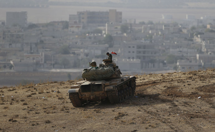 A Turkish soldier sits on top of a tank, with the Syrian town of Kobani in the background, as seen from the southeastern town of Suruc close to the Mursitpinar border crossing on the Turkish-Syrian border October 10, 2014. (Reuters/Umit Bektas)