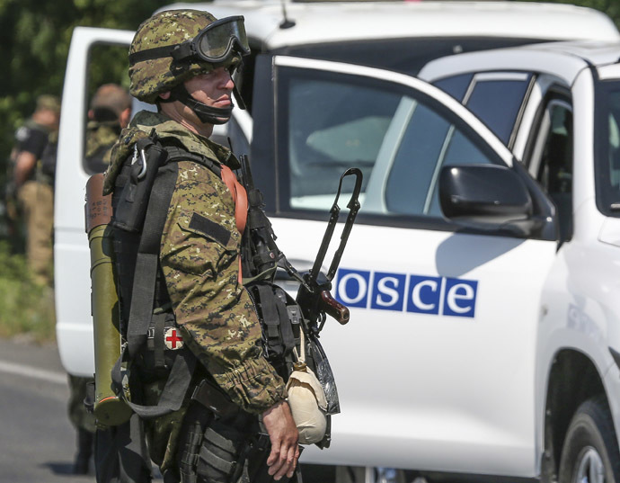 An armed pro-Russian separatist looks back next to a vehicle of the Organisation for Security and Cooperation in Europe's (OSCE) monitoring mission in Ukraine, on the way to the site in eastern Ukraine where the downed Malaysia Airlines flight MH17 crashed, outside Donetsk, July 30, 2014. (Reuters/Sergei Karpukhin)