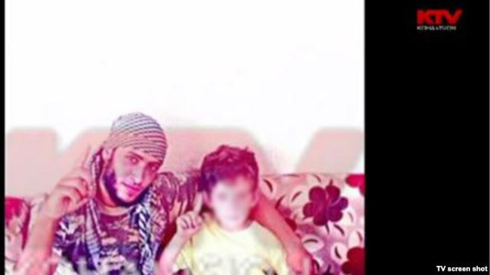8 year-old Erion Zena and an unidentified man holding up one finger in the Islamic State salute. Screenshot from Kosovo TV