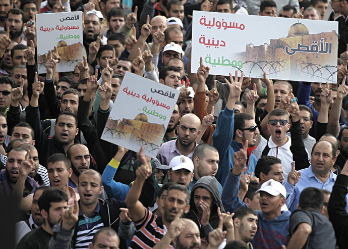 Palestinians shout slogans holding placards as they gather near the entrance of al-Aqsa mosque compound to protest after authorities restricted access to the esplanade on October 15, 2014 outside Jerusalem's Old City. (AFP Photo/Ahmad Gharabli)