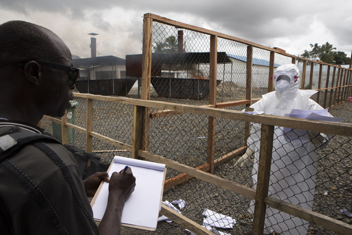 A health worker (R) wearing protective equipment provides his colleague with patient data at the end of his shift from the Ebola treatment centre at the Island Clinic in Monrovia, September 30, 2014. (Reuters/Christopher Black)