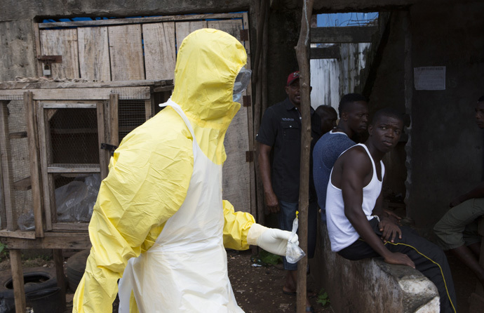 A health worker in protective equipment carries a sample taken from the body of someone who is suspected to have died from Ebola virus, near Rokupa Hospital, Freetown October 6, 2014. (Reuters/Christopher Black)